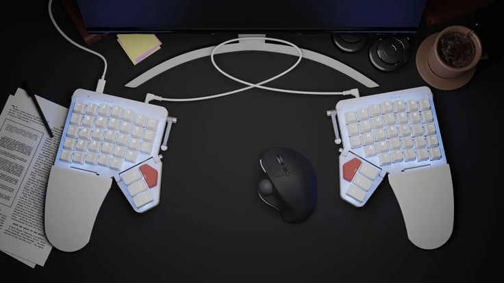Left and Right Moonlander in a desk, with a trackball between the two halves